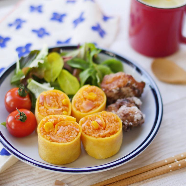 ひと口サイズに切られたくるくるオムライスとサラダなどを盛った皿