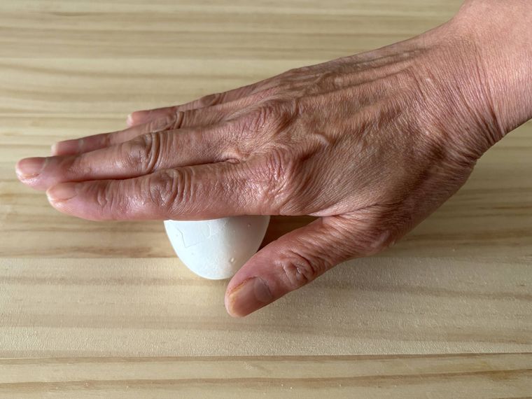 ゆで卵をまな板の上で転がしている写真