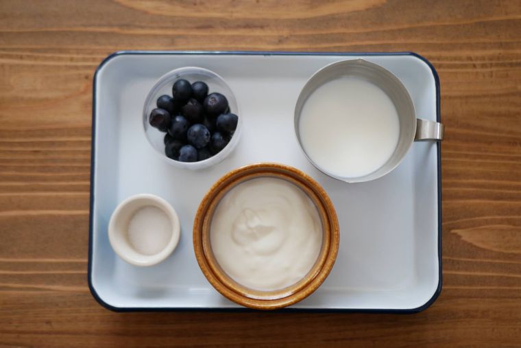琺瑯バットの上にブルーベリー、牛乳、ヨーグルト、砂糖が置かれている