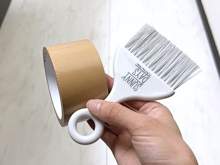 ミニほうきとガムテープを手で持っている様子