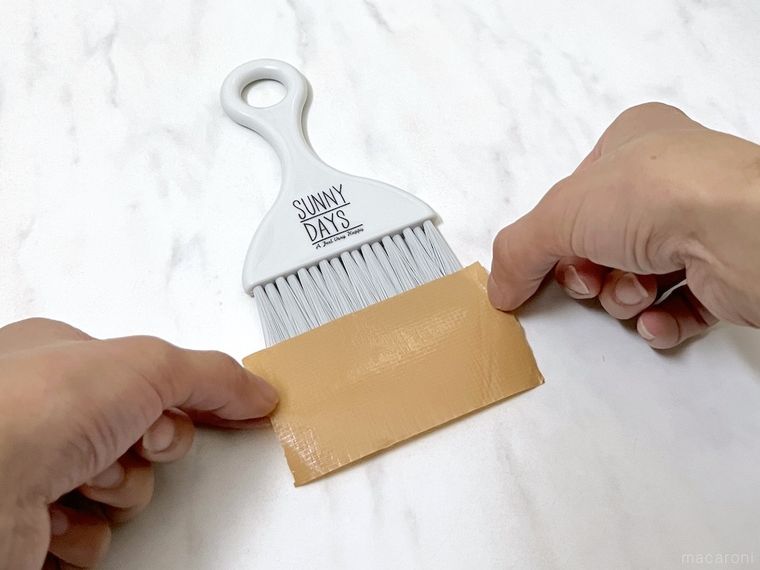 ミニほうきにガムテープを貼っている様子