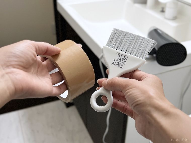 ガムテープとミニほうきを手で持っている様子