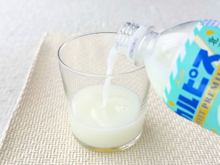 グラスにカルピス SWEET PREMIUM 北海道生クリームのプリン風を注いでいる様子