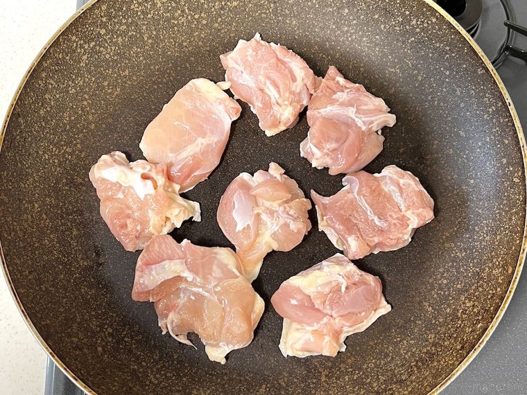ひと口大に切った鶏肉をフライパンに入れた様子
