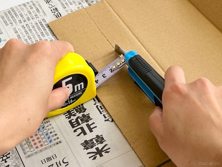 メジャーとカッターで段ボールを切っている様子