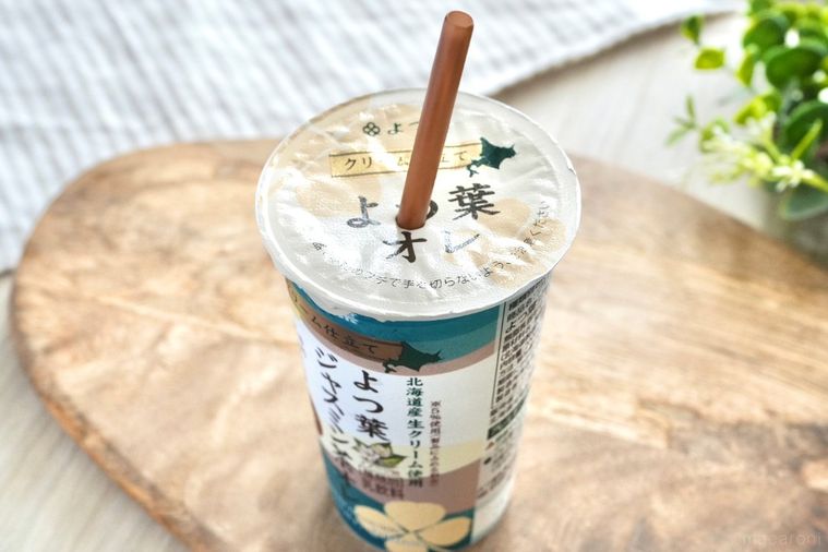木のカッティングボードにのったジャスミン茶オレ入りのエメラルド色のカップに茶色いストローが刺さった様子