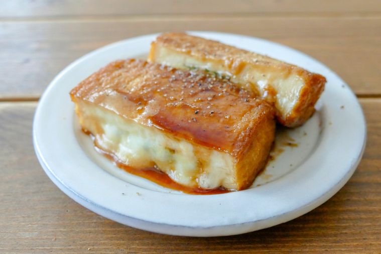 甘辛く味付けした厚揚げのはさみ焼きがふた切れのっている白い皿