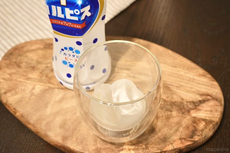 木のカッティングボードにのったカルピスとロックアイス入りのグラス