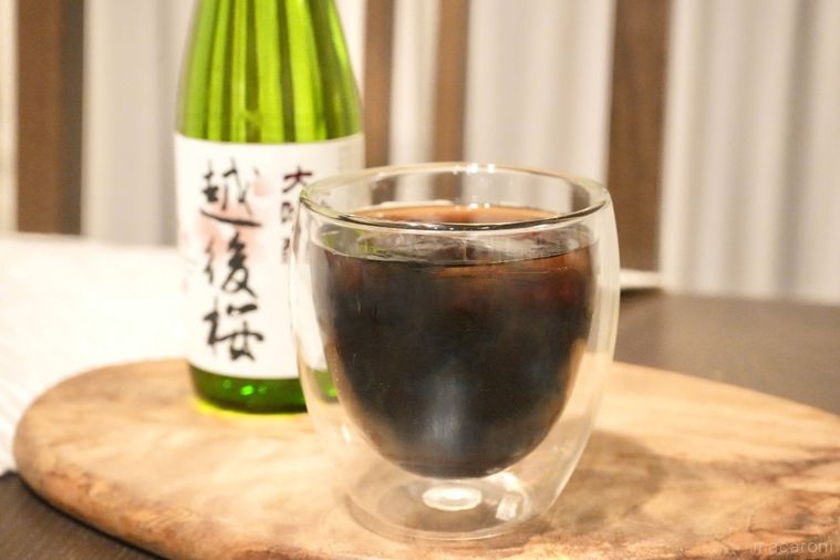 木のカッティングボードにのった氷とコーヒーと日本酒入りのグラスと緑色の瓶