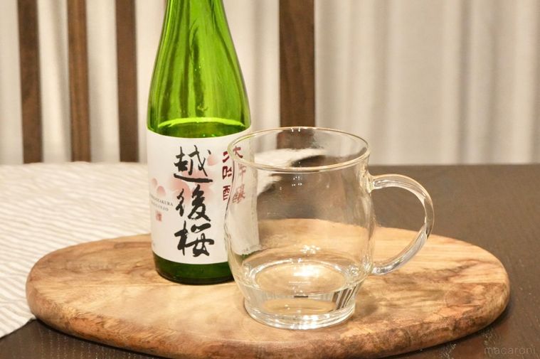 木のカッティングボードにのったグラスマグと日本酒の緑色の瓶