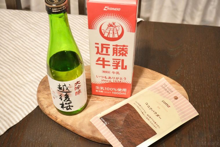 木のカッティングボードにのった日本酒の緑色の瓶と赤い牛乳パックとココアパウダーの袋