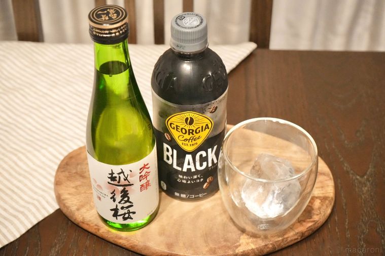 木のカッティングボードにのった日本酒の緑の瓶とブラックコーヒーのペットボトルと氷入りのグラス