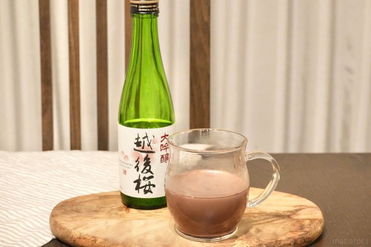 木のカッティングボードにのったココア入りのグラスと日本酒の緑色の瓶