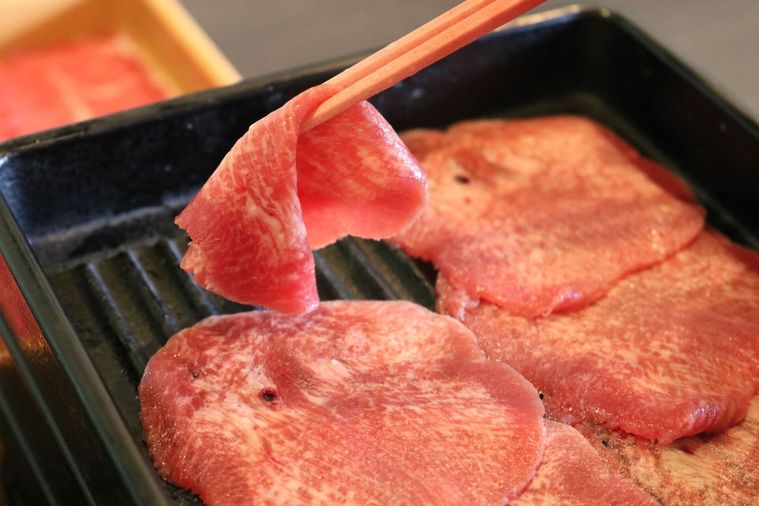 牛タンを箸で持っている