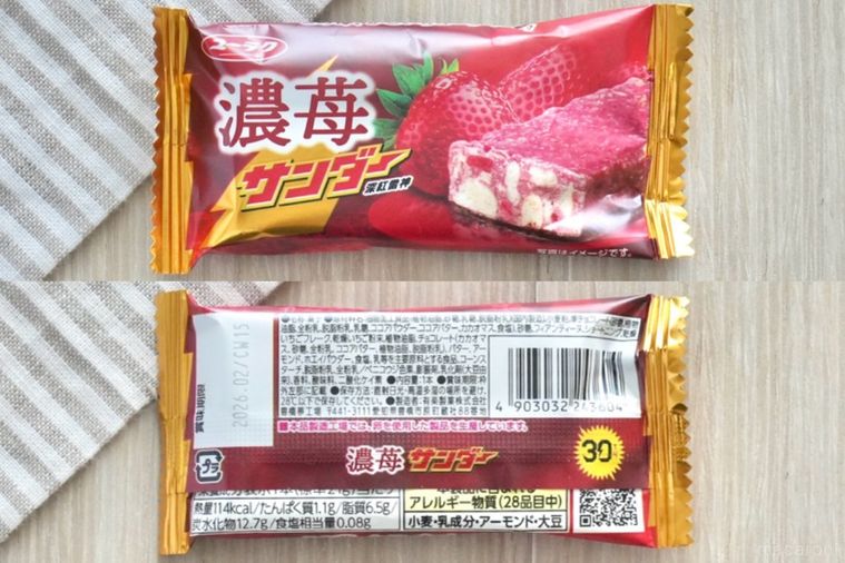 白い木目調のテーブルとストライプの布と苺味のブラックサンダーと成分表示