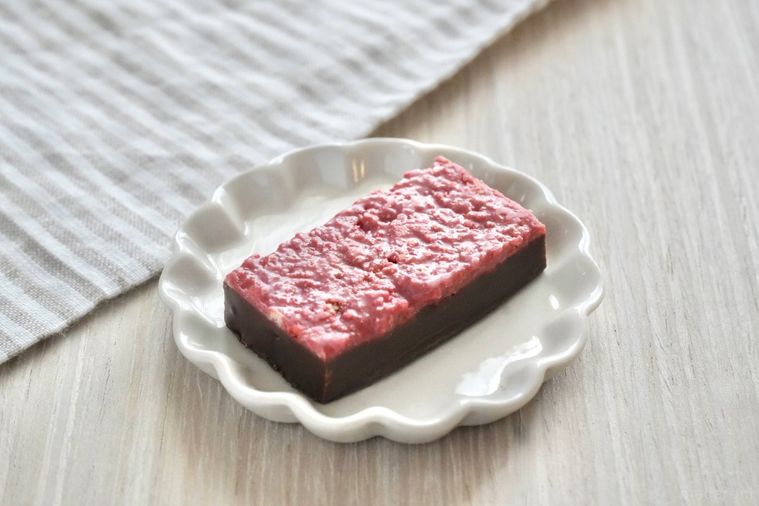 白い木目調のテーブルとストライプの布と苺味のブラックサンダーと白い小皿