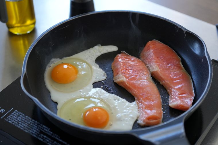 目玉焼きと鮭を焼いている