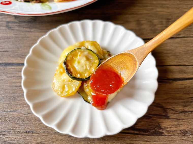 ズッキーニ、じゃがいも、チーズのフライパン蒸しにケチャップを添える様子