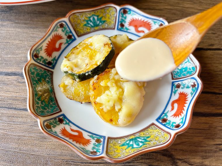ズッキーニ、じゃがいも、チーズのフライパン蒸しにめんつゆマヨをかける様子