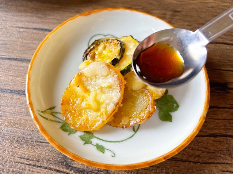 ズッキーニ、じゃがいも、チーズのフライパン蒸しにポン酢しょうゆをかける様子