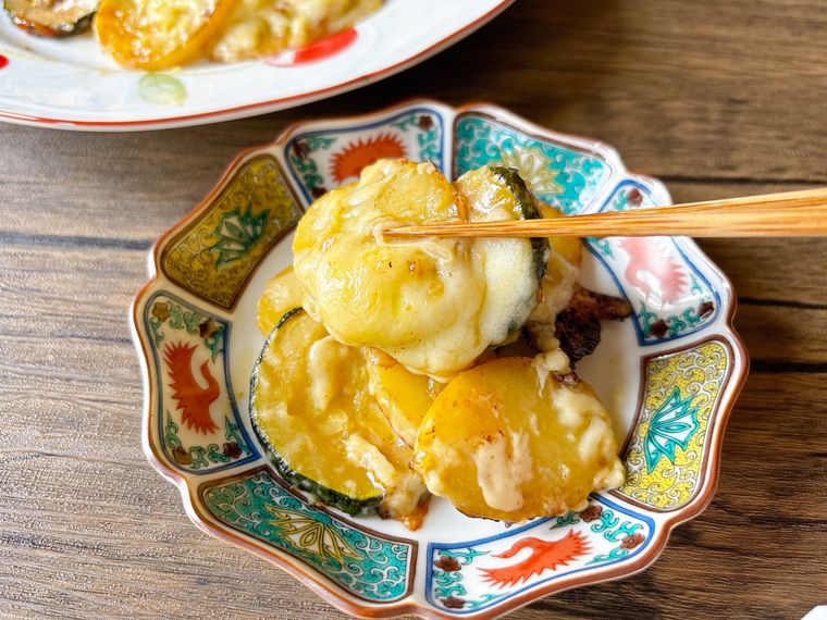 ズッキーニ、じゃがいも、チーズのフライパン蒸しを箸で持ち上げる様子