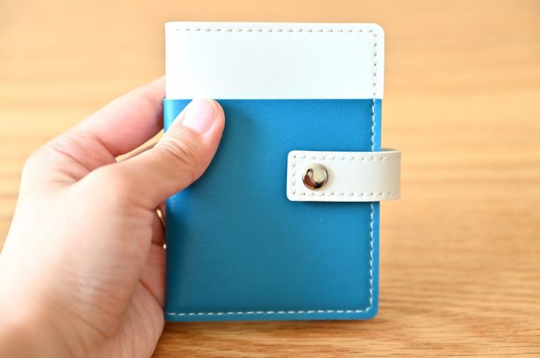 バイカラーのカードケースを手に持っている