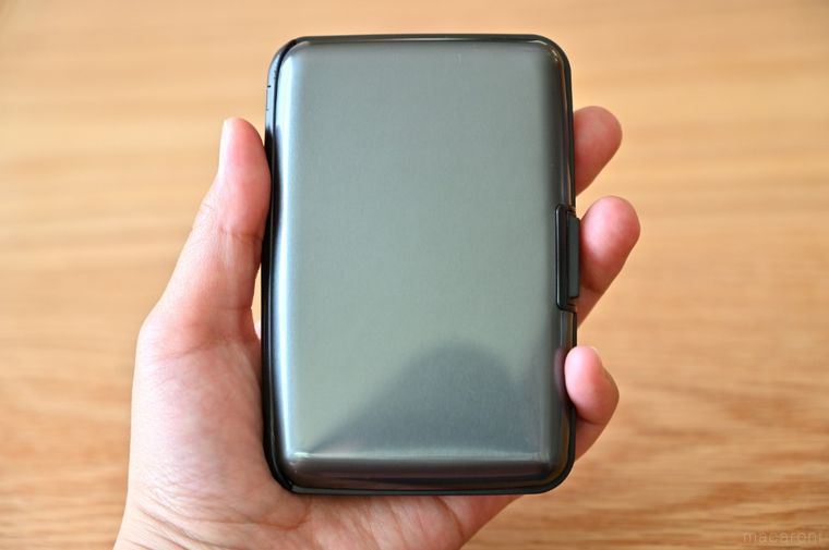 黒いカードケースを手に持っている