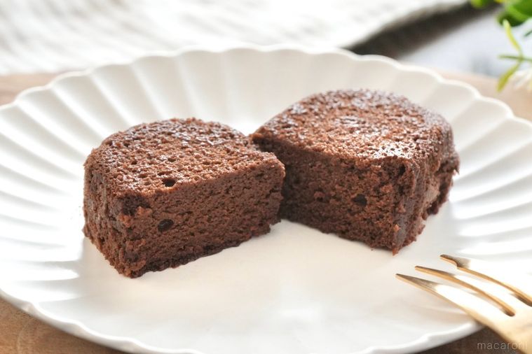 木のカッティングボードと白い皿にのった泡食感のショコラケーキの断面と金のフォークとストライプの布とグリーン