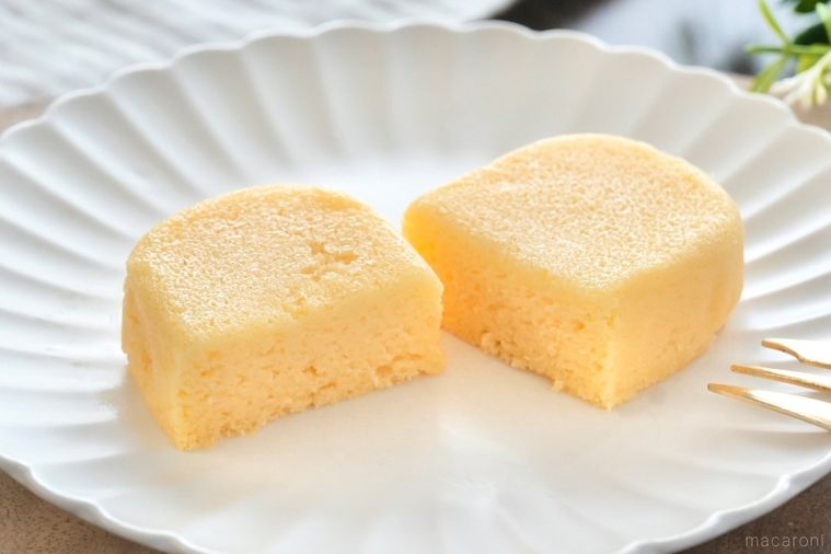 木のカッティングボードと白い皿にのった泡食感のチーズケーキの断面と金のフォークとストライプの布とグリーン