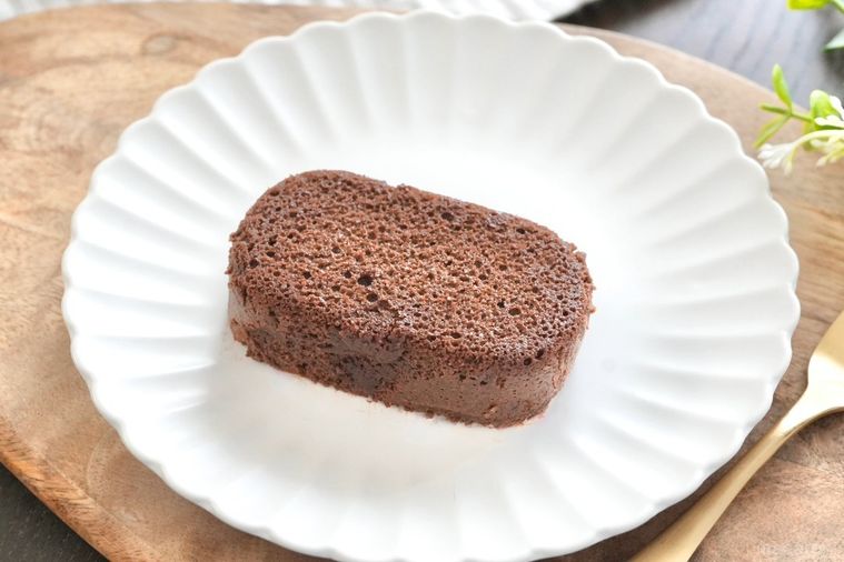 木のカッティングボードと白い皿にのった泡食感のショコラケーキと金のフォークとストライプの布とグリーン