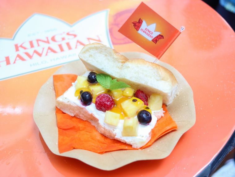 オレンジ色の紙ナプキンを敷いた紙皿に盛り付けられているフルーツサンドスライダー