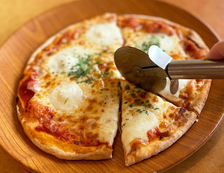 サイゼリヤのピザをピザカッターでカットしているところ