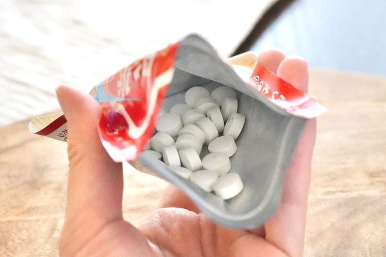 木のカッティングボードと梅昆布茶味のタブレットの赤いパッケージを手に持つ様子