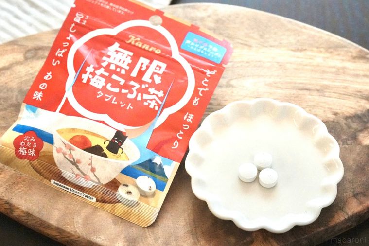 木のカッティングボードにのった白い小皿と赤いパッケージと梅こぶ茶味のタブレット