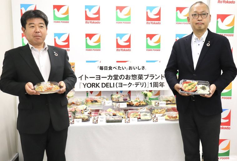 男性2名が惣菜を持っている