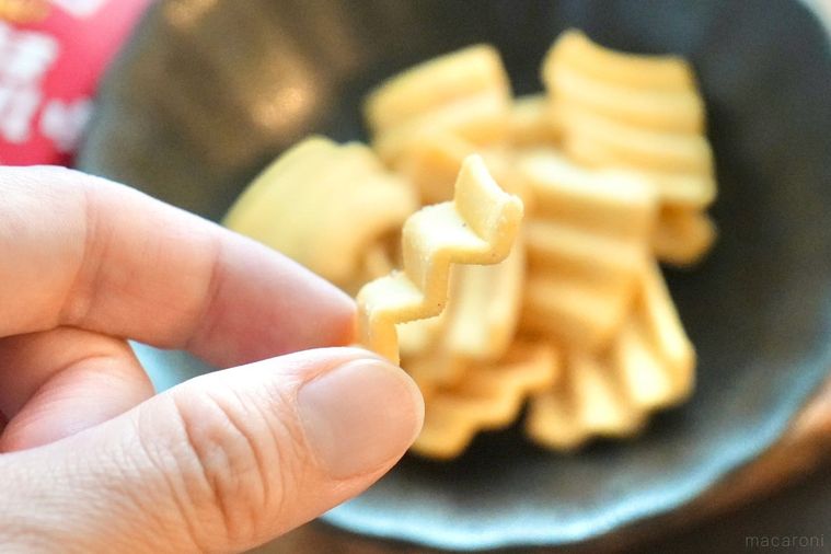 黒い器に盛られた梅味のポテトスナックを手に持つ様子