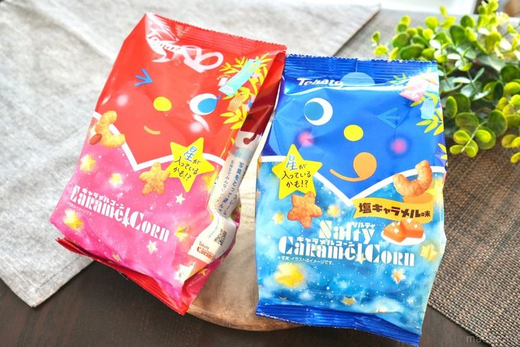 木のカッティングボードにのった赤色と青色の七夕限定パッケージのキャラメルコーンとソルティキャラメルコーンとグレーの布