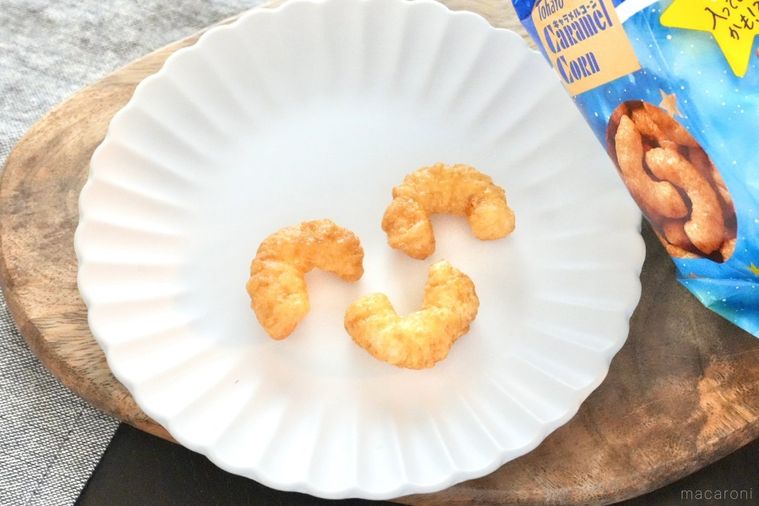 木のカッティングボードと白い皿にのったキャラメルコーンと青いパッケージとグレーの布