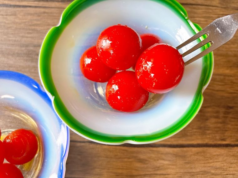 緑色のガラスの器に盛られたミニトマトのはちみつレモン漬けを食べる様子