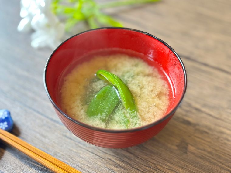 赤色のお椀に盛られたピーマンの味噌汁