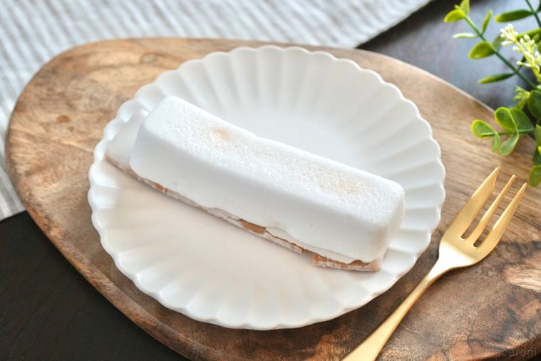 木のカッティングボードと白い皿にのった白いレモン味のスティックケーキと金のフォークとストライプの布