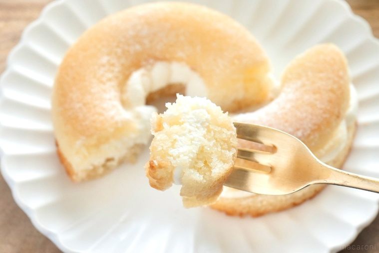 白い皿にのった焼きドーナツサンドを金のフォークで食べる様子