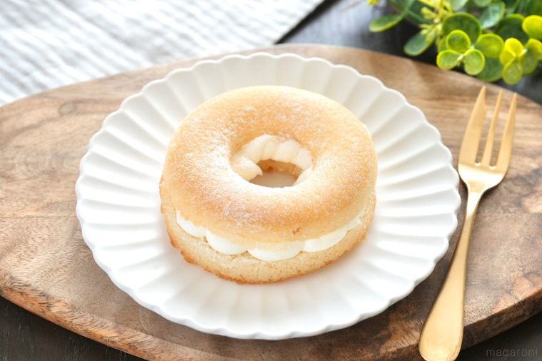 木のカッティングボードと白い皿にのった焼きドーナツサンドと金のフォークとストライプの布とグリーン