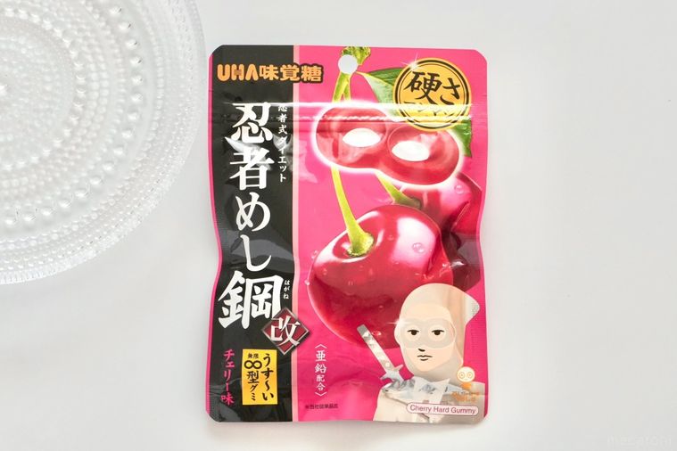 白い背景にチェリー味のグミのピンク色のパッケージとガラスの器