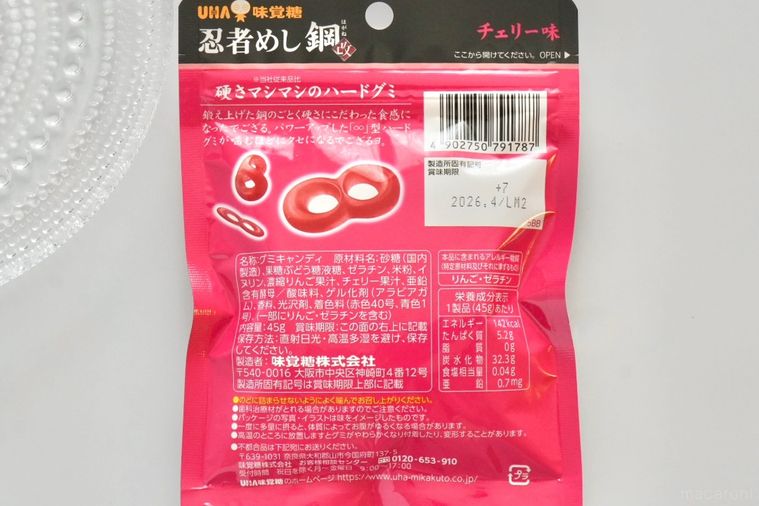 白い背景にチェリー味のグミのピンク色のパッケージの成分表示とガラスの器