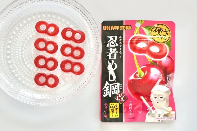 白い背景とガラスの器に並べられた型のチェリー味ハードグミとピンク色のパッケージ