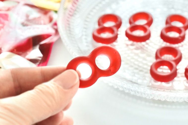 ガラスの器に置かれたチェリー味のハードグミを手に持つ様子