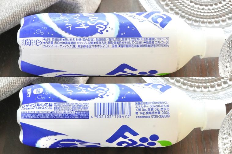 茶色いテーブルの上のアンバサファンタの白と青色のペットボトルとガラスの器とグレーの布