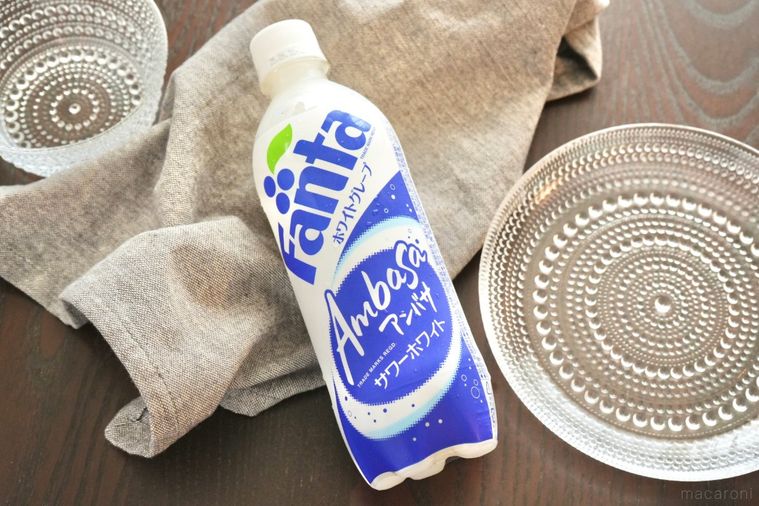 茶色いテーブルの上のアンバサファンタの白と青色のペットボトルとガラスの器とグレーの布