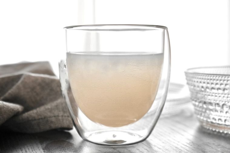 茶色いテーブルにのった乳性炭酸飲料のアンバサファンタが入ったグラスとグレーの布